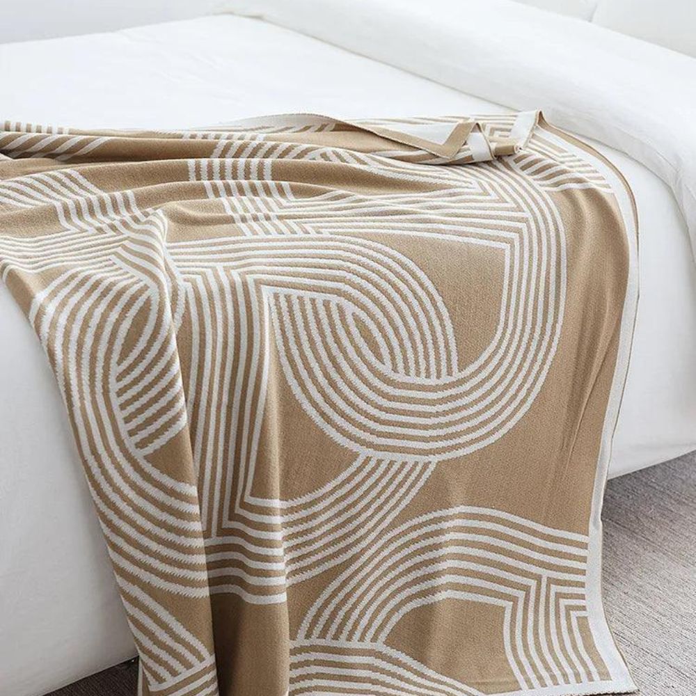 Vendbar strikket plaid med geometrisk labyrintmønster over sofa