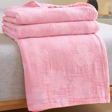 Sengetæppe i økologisk bomuld med kløverblade på en redt seng