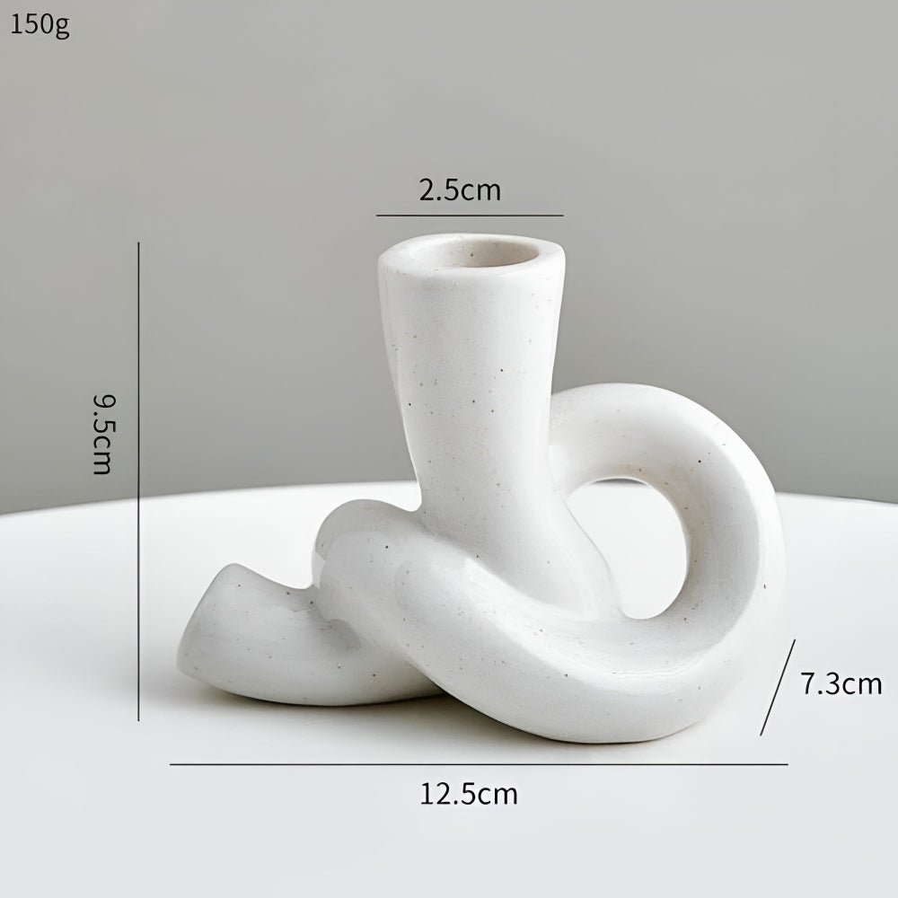 Neutral lysestage i keramik med knudedesign på bord