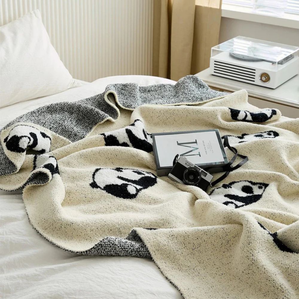 Strikket tæppe med yndigt pandamotiv over sofa