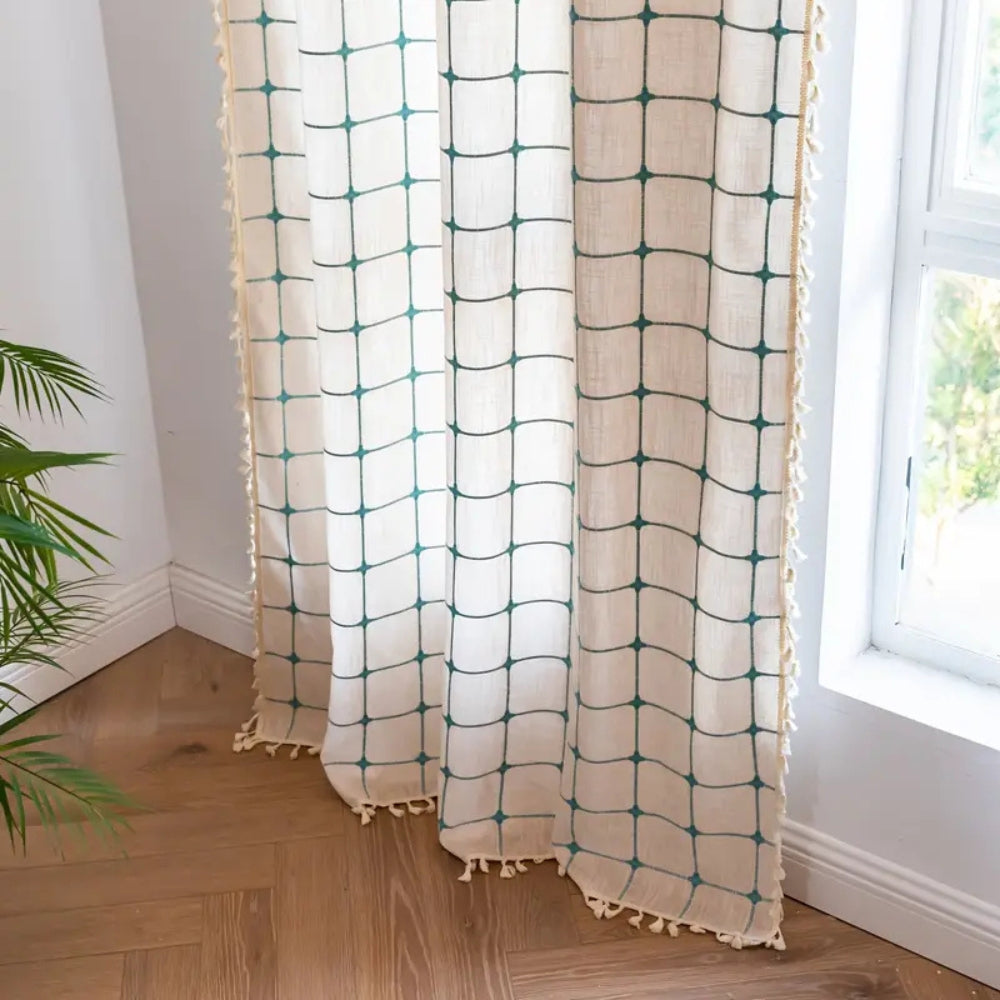 Boho gardin med turkis broderi og kvaster foran et vindue