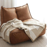 Vendbar strikket plaid med geometrisk labyrintmønster over sofa