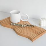Nordisk træbakke med bølgemønster og kaffe på spisebordet