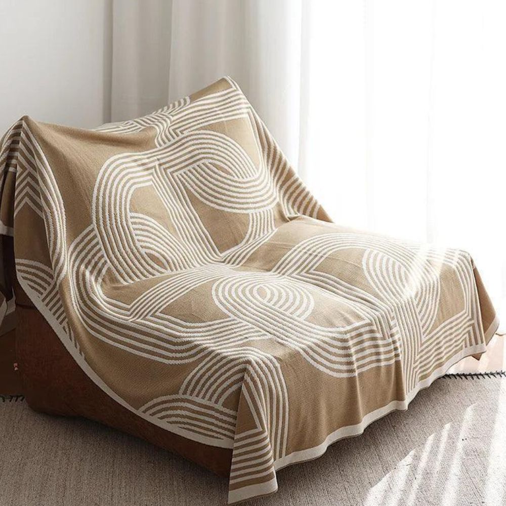 Vendbar strikket plaid med geometrisk labyrintmønster over sofa