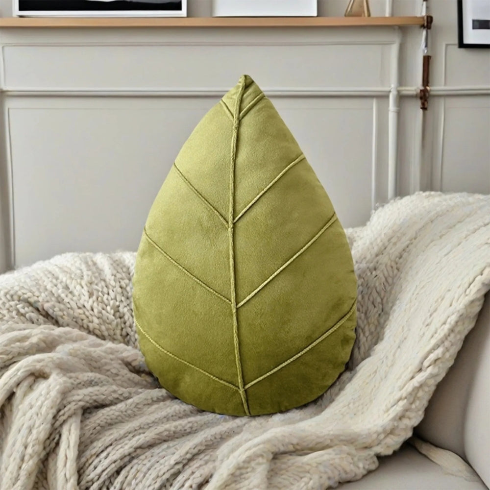 Grøn bladformet pyntepude i blød mikrofiber på en sofa