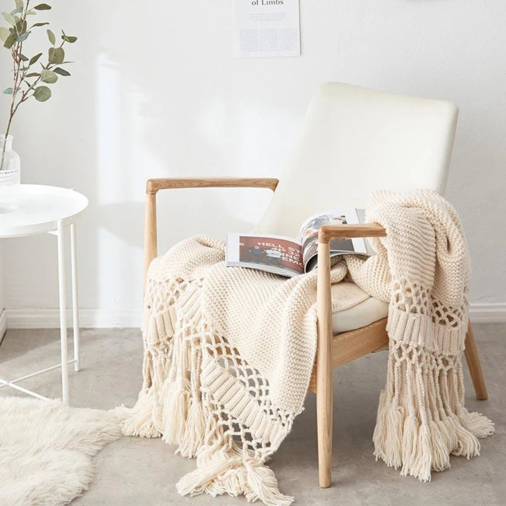 Strikket plaid med kvaster draperet over sofa