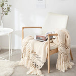 Strikket plaid med kvaster draperet over sofa