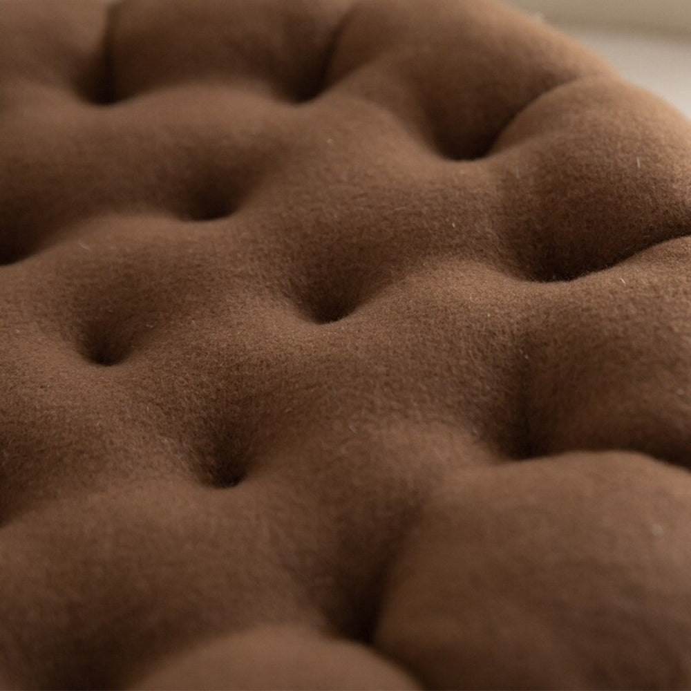 Blød keksformet pyntepude i beige på en sofa