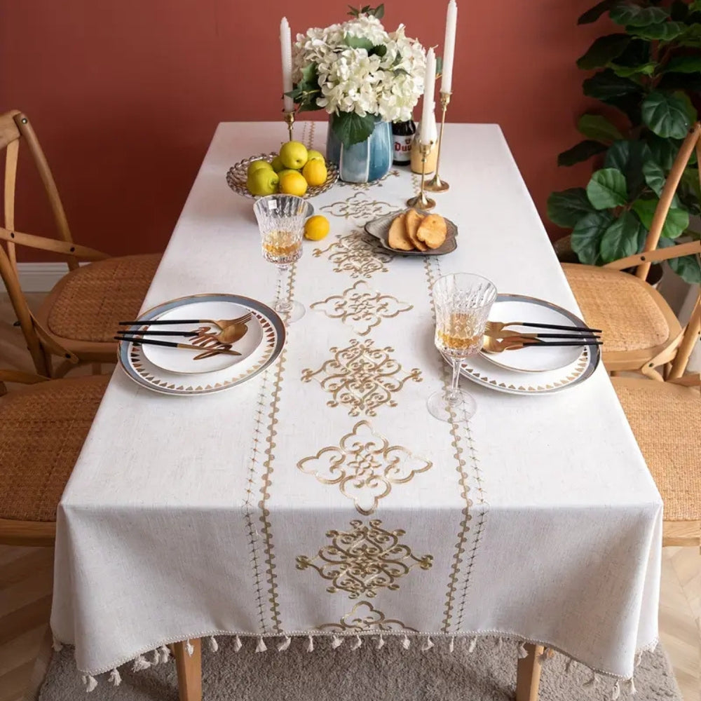 Elegant broderet dug med elfenbensfarvede kvaster på spisebord
