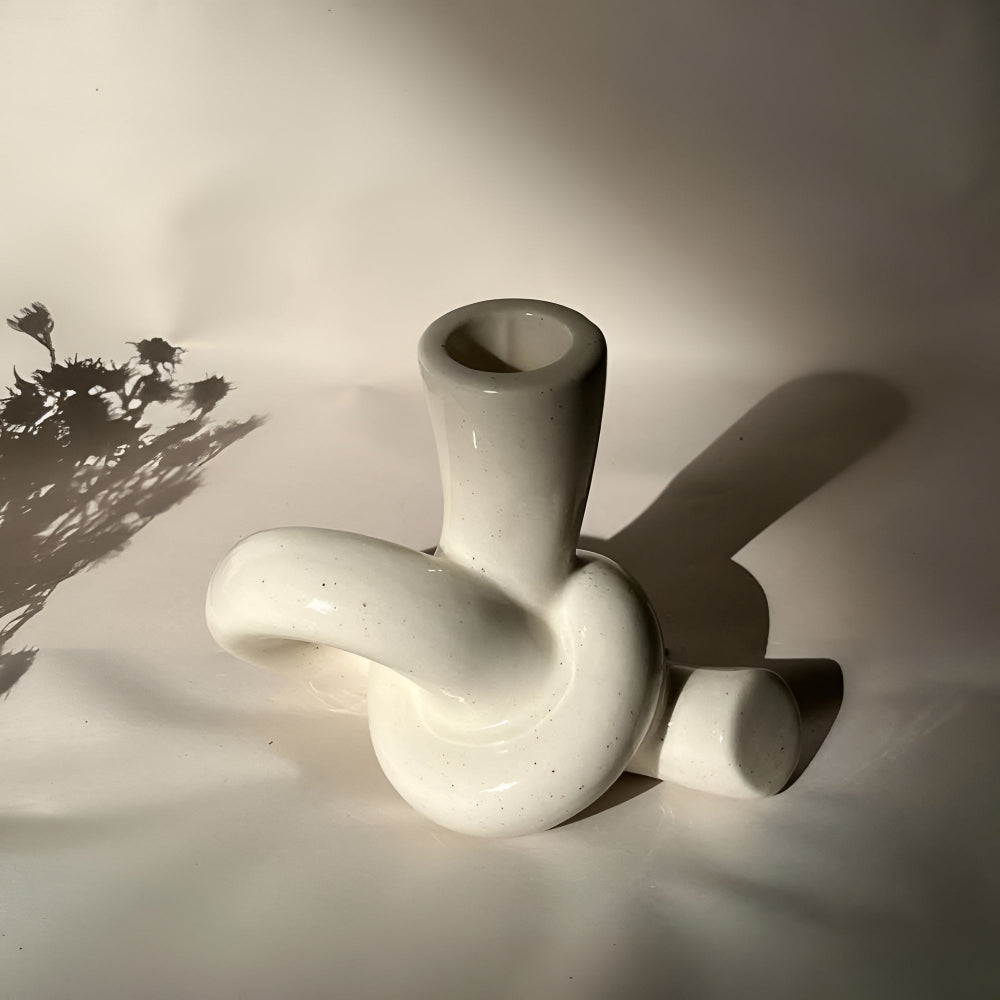 Neutral lysestage i keramik med knudedesign på bord