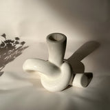 Neutral lysestage i keramik med knudedesign på bord