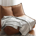 Vendbar strikket plaid med geometrisk labyrintmønster over sofa