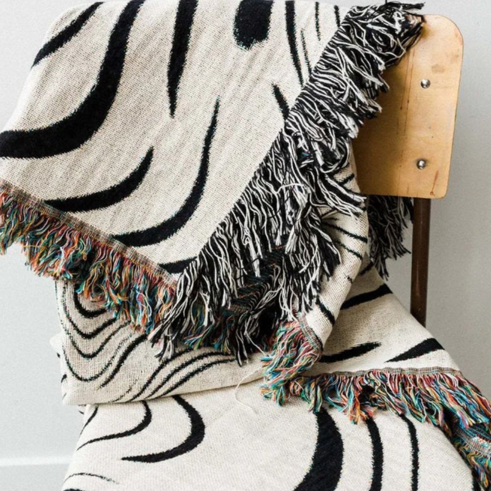Vævet bomuldsplaid med sort og offwhite marmormønster over en sofa