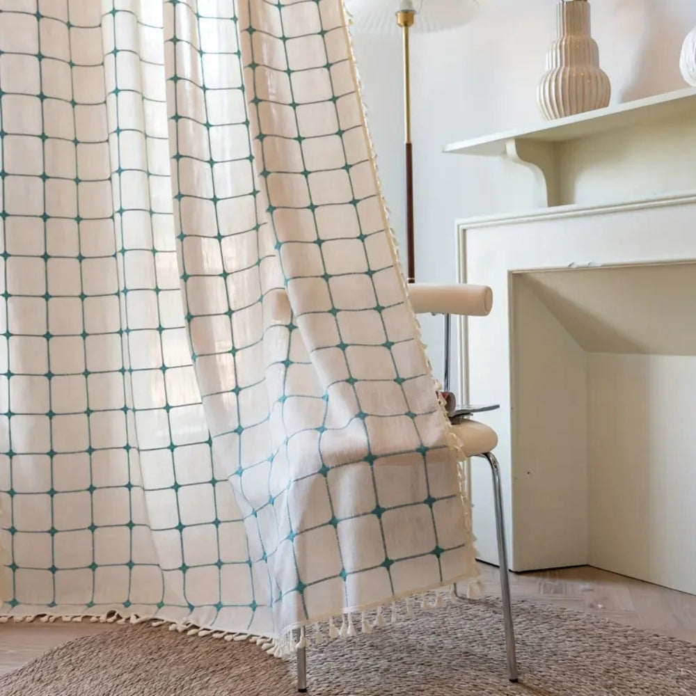 Boho gardin med turkis broderi og kvaster foran et vindue