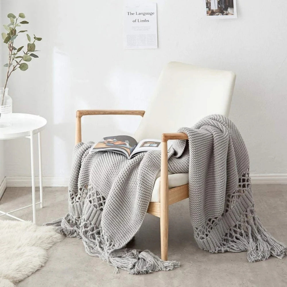 Strikket plaid med kvaster draperet over sofa