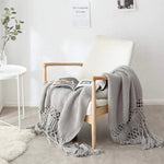 Strikket plaid med kvaster draperet over sofa