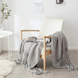 Strikket plaid med kvaster draperet over sofa