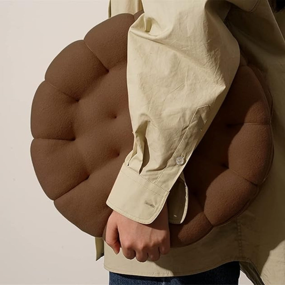 Blød keksformet pyntepude i beige på en sofa