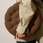 Blød keksformet pyntepude i beige på en sofa