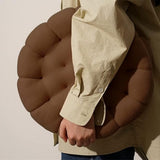Blød keksformet pyntepude i beige på en sofa