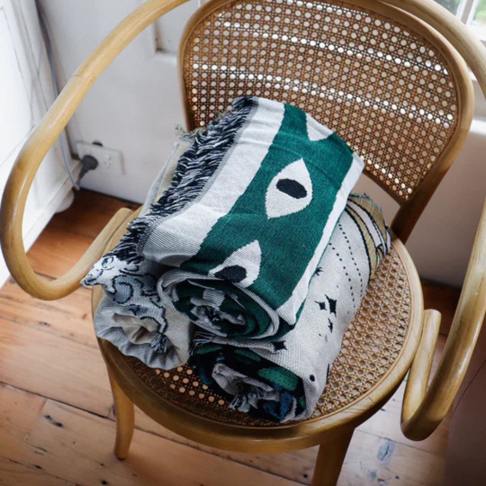 Grøn og grå bomuldsplaid med slangemønster og kvaster på sofa