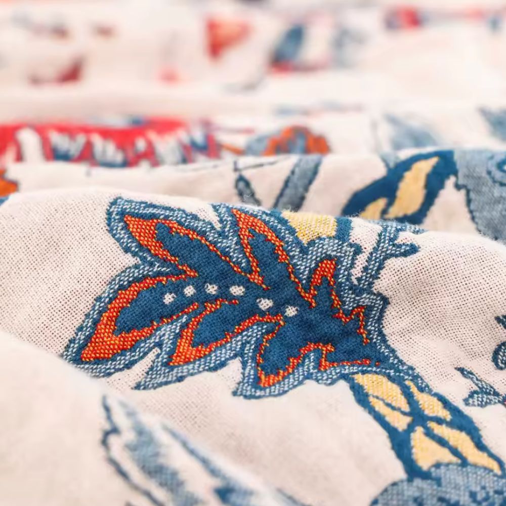 Bomuldstæppe med retro blomsterprint og åndbar struktur over sofa