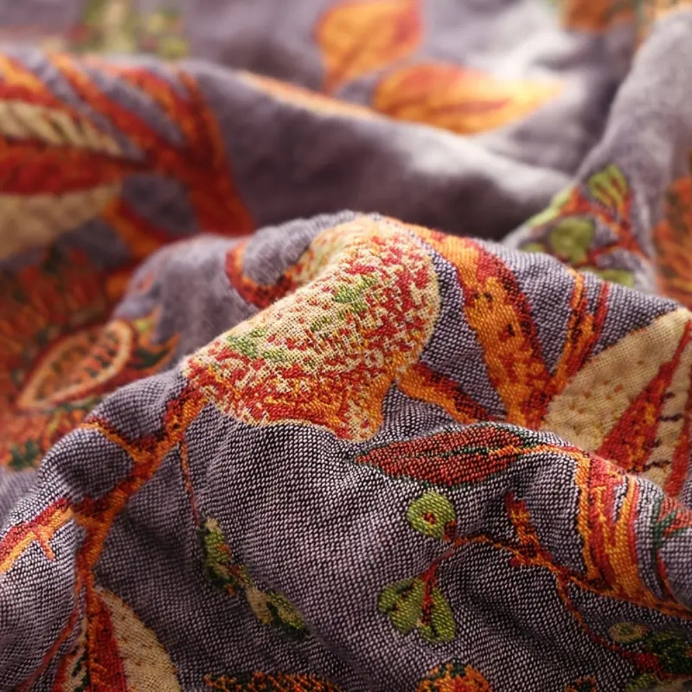 Vendbart bomuldstæppe med blomsterjacquard og kvaster over sofa