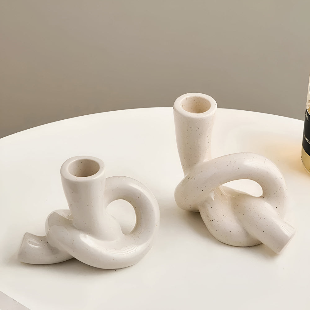 Neutral lysestage i keramik med knudedesign på bord