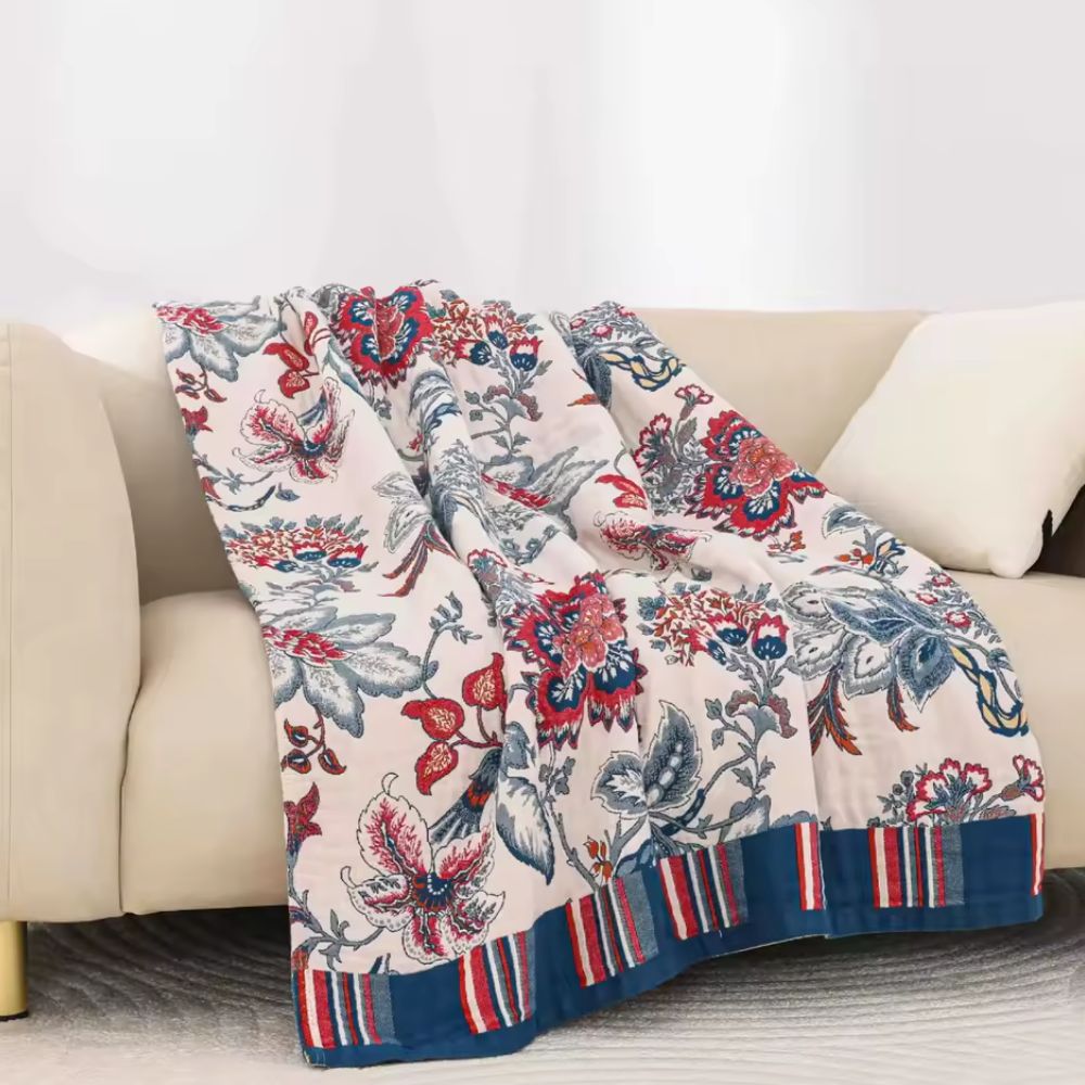 Bomuldstæppe med retro blomsterprint og åndbar struktur over sofa