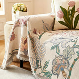 Vendbart sofabetræk med blomsterjacquard og kvaster på sofa