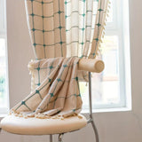 Boho gardin med turkis broderi og kvaster foran et vindue