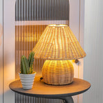 Håndvævet rattan bordlampe, der giver varmt lys i stuen