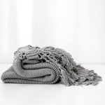 Strikket plaid med kvaster draperet over sofa