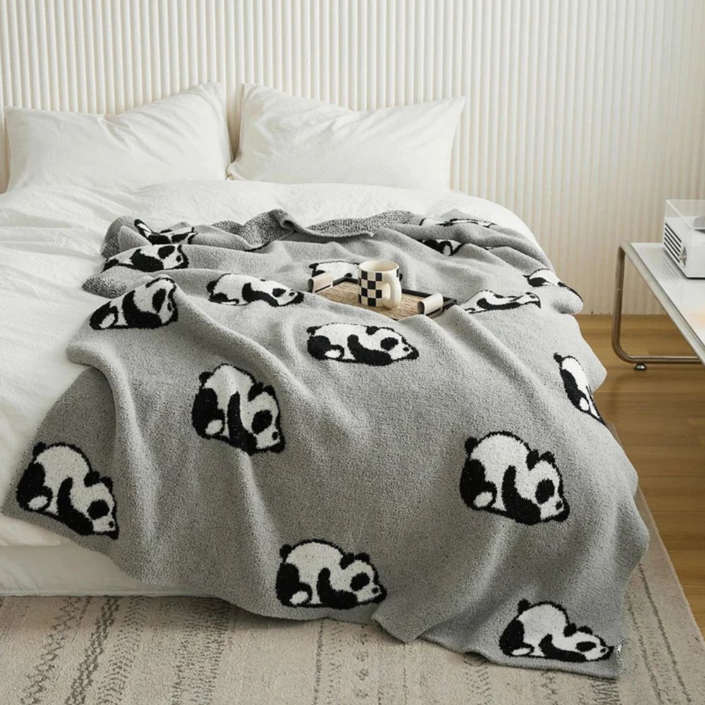 Strikket tæppe med yndigt pandamotiv over sofa