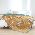Blødt tæppe med blomstermønster og kvaster over en sofa
