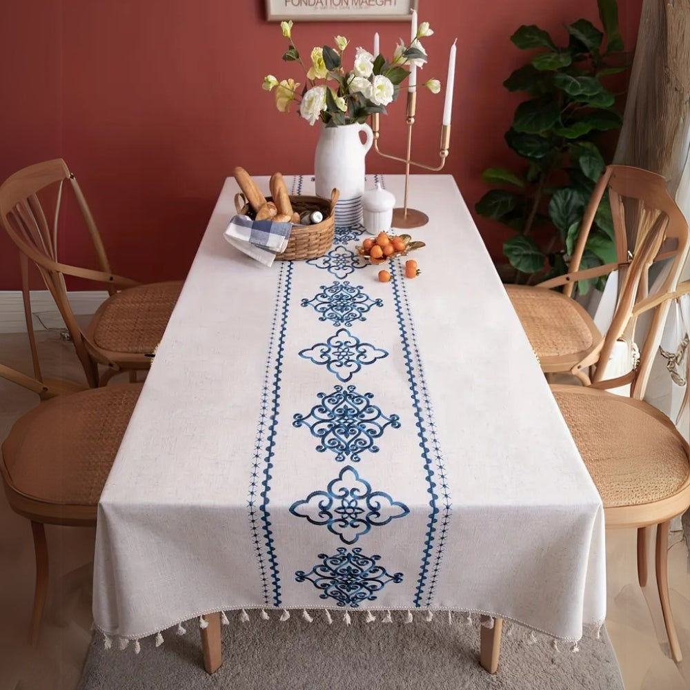 Elegant broderet dug med elfenbensfarvede kvaster på spisebord