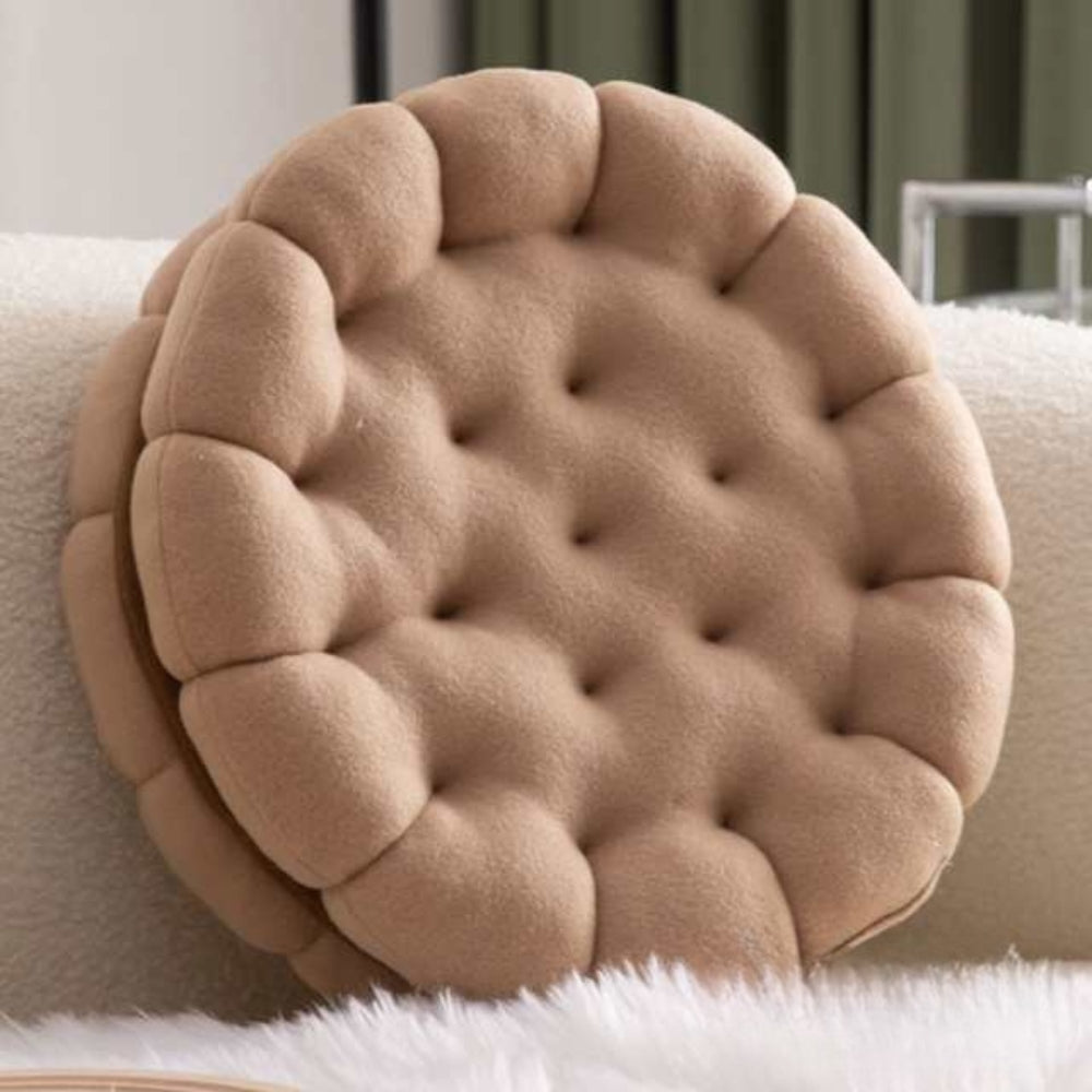 Blød keksformet pyntepude i beige på en sofa
