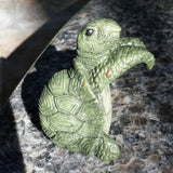 Hængende skildpadde i polyresin på kanten af en urtepotte