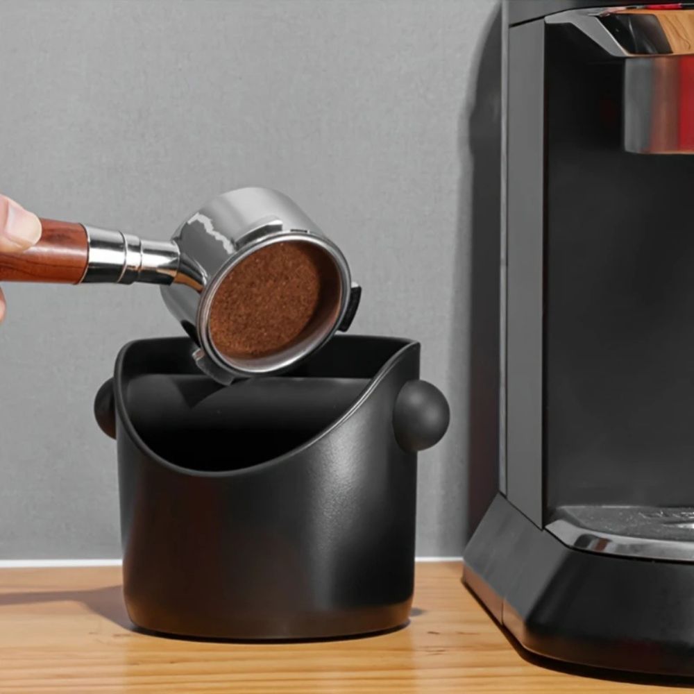Mat knockbox til kaffegrums med slagstang ved siden af espressomaskine
