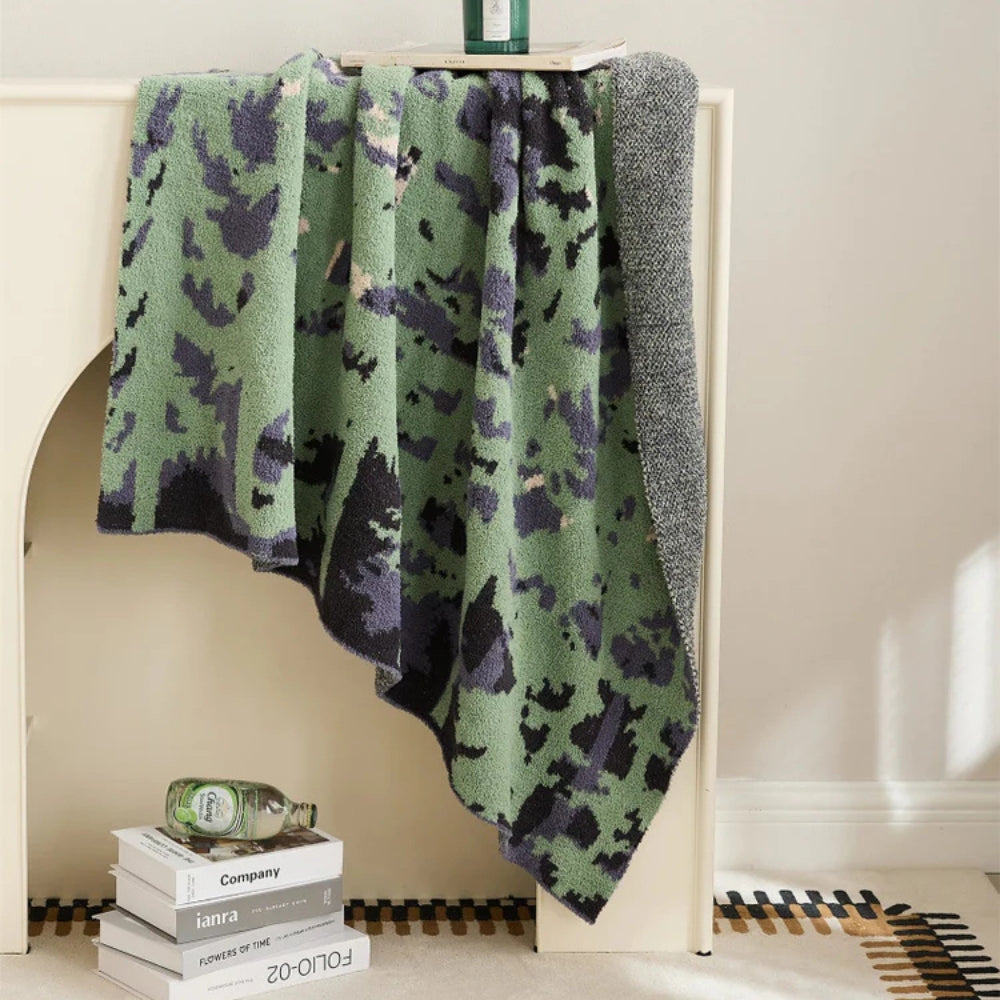 Blød strikket plaid med naturinspireret mønster over sofaen
