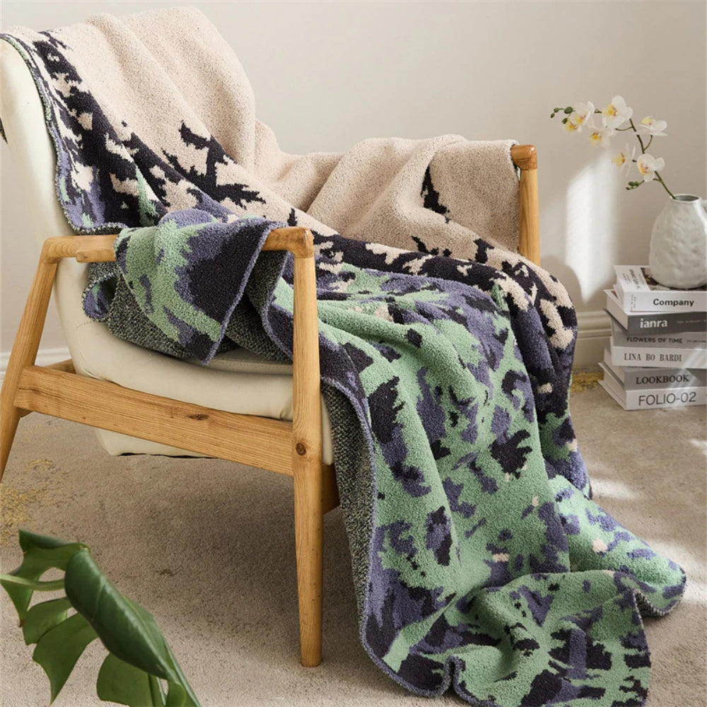 Blød strikket plaid med naturinspireret mønster over sofaen