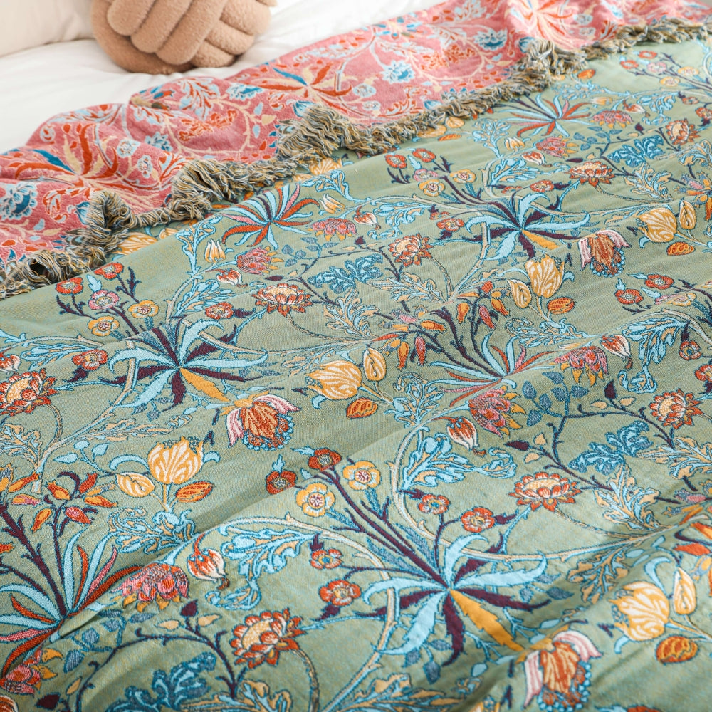 Vendbart bomuldstæppe med blomsterjacquard og kvaster på seng