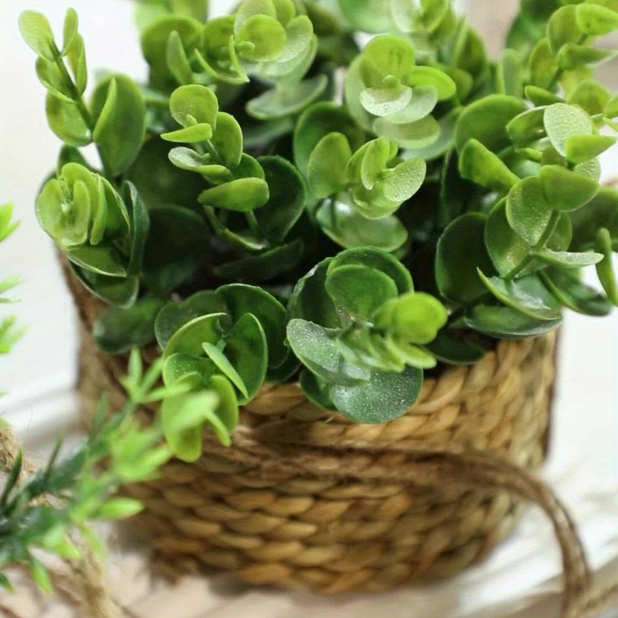 Hængende kunstig plante i vævet kurvepotte på altan