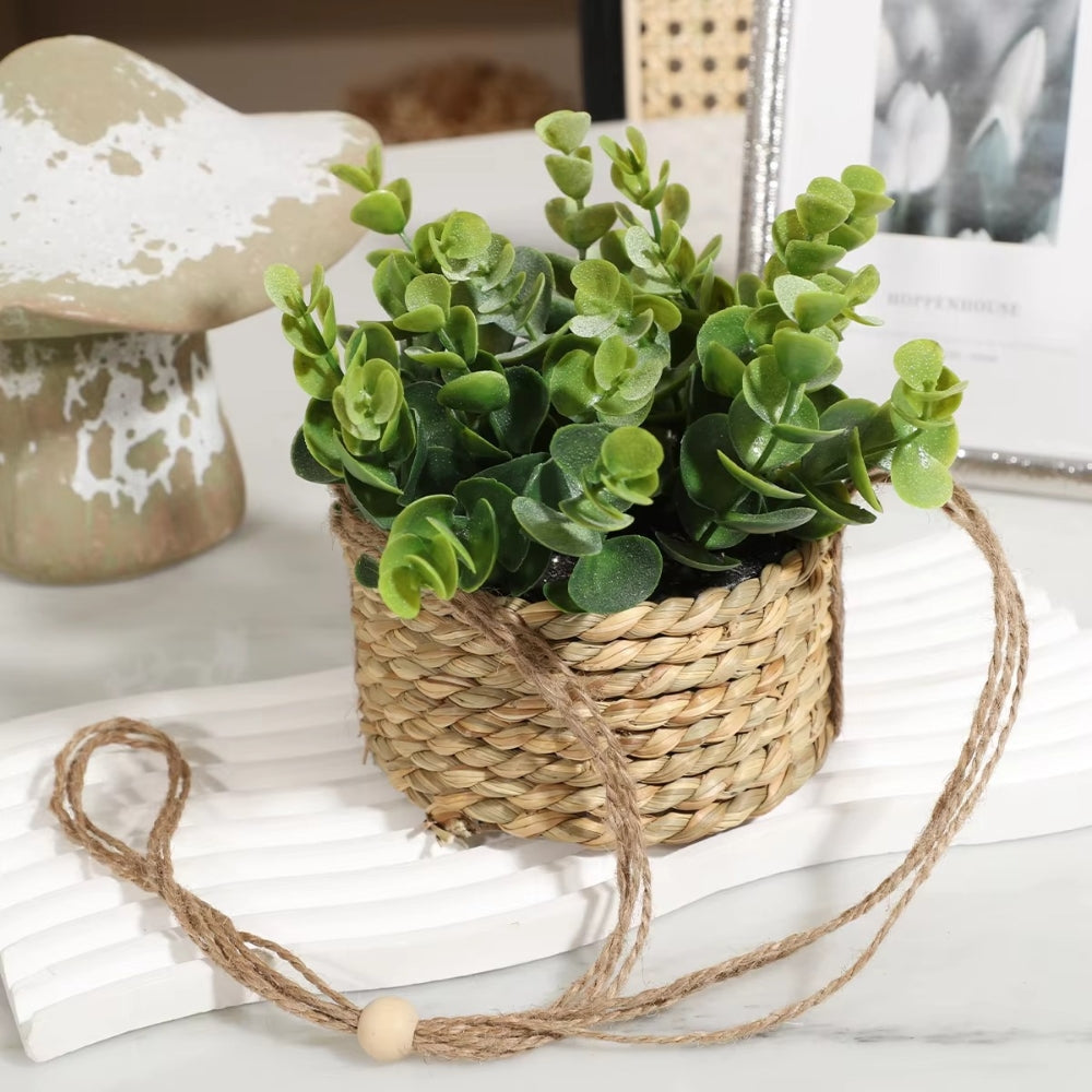 Hængende kunstig plante i vævet kurvepotte på altan