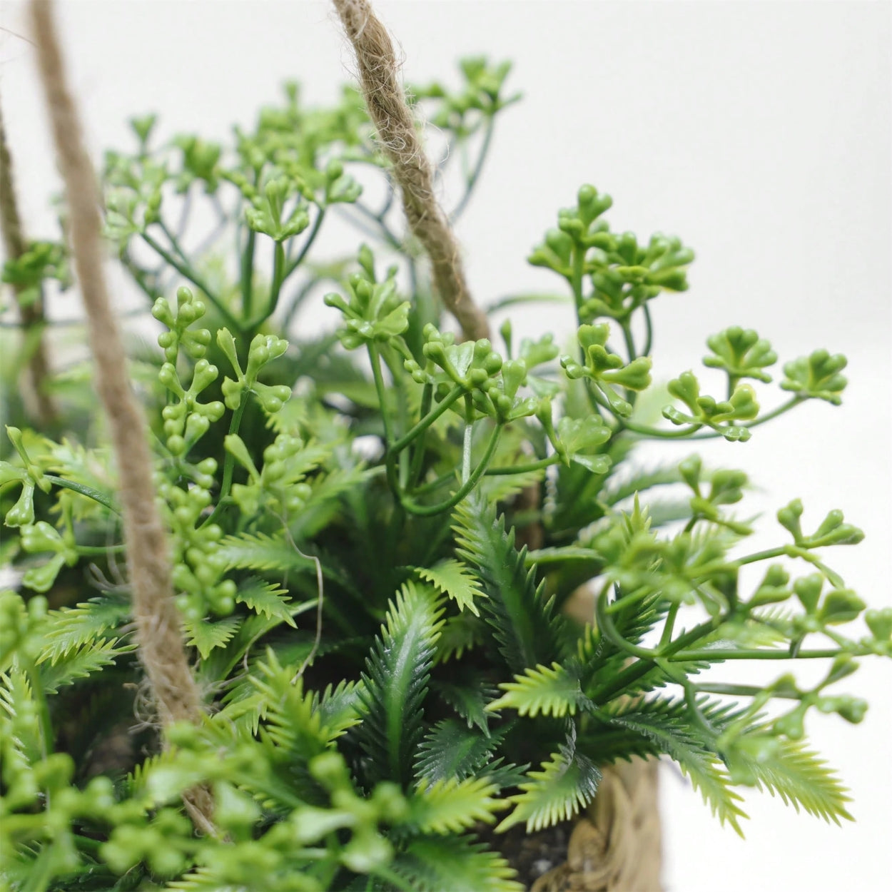 Hængende kunstig plante i vævet kurvepotte på altan