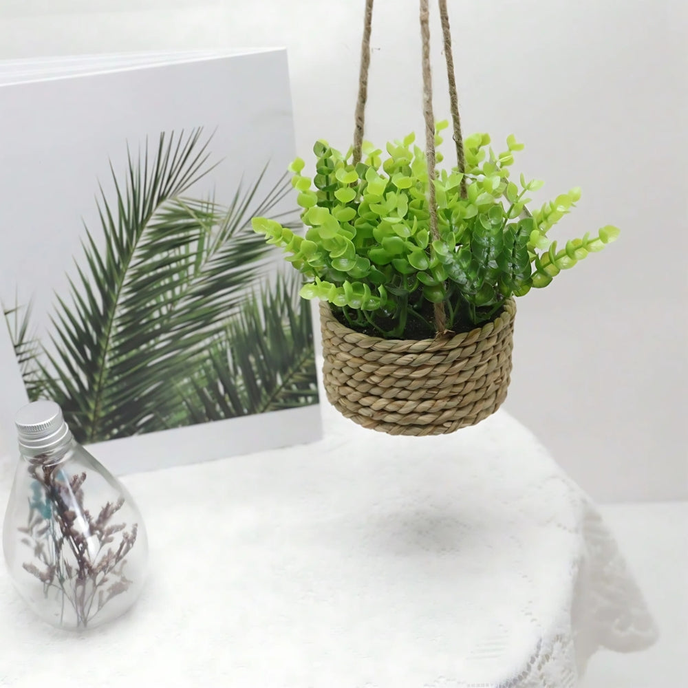 Hængende kunstig plante i vævet kurvepotte på altan