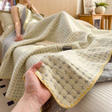 Vendbart bomuldstæppe i matelassé med geometrisk mønster over sofa
