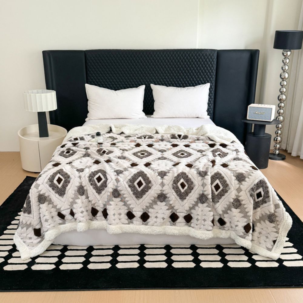 Plaid i to lag med geometrisk rudemønster over en sofa