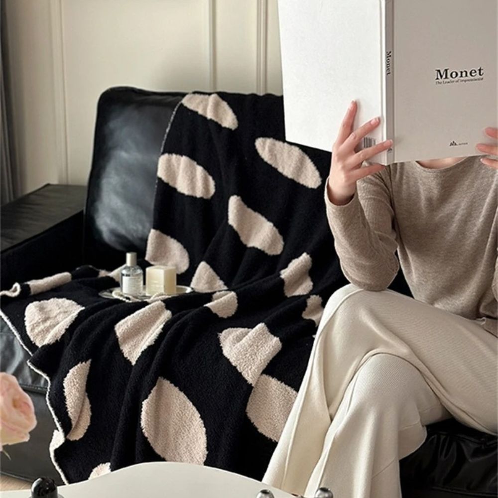 Sort-hvid plaid i fleece med prikker over sofa