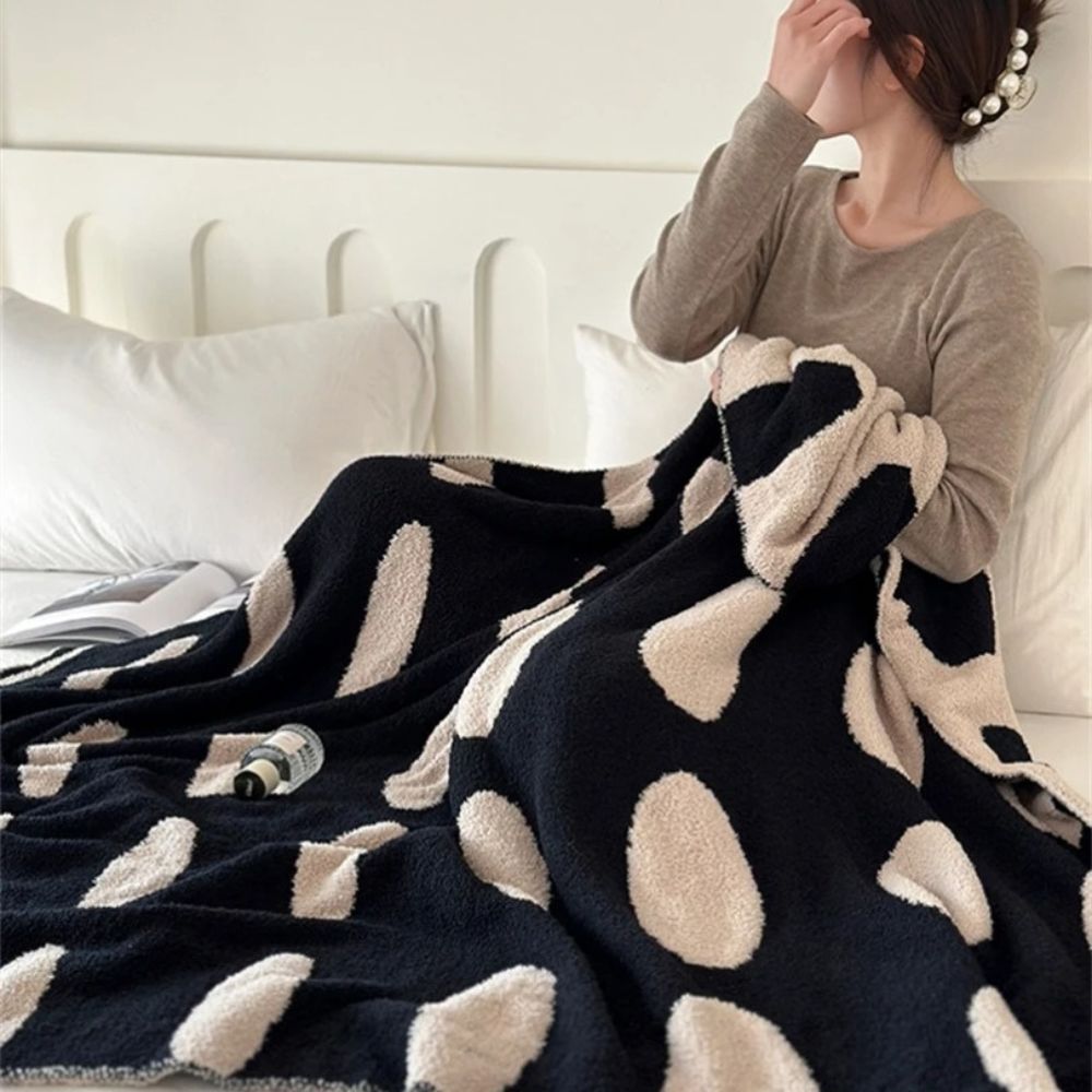 Sort-hvid plaid i fleece med prikker over sofa